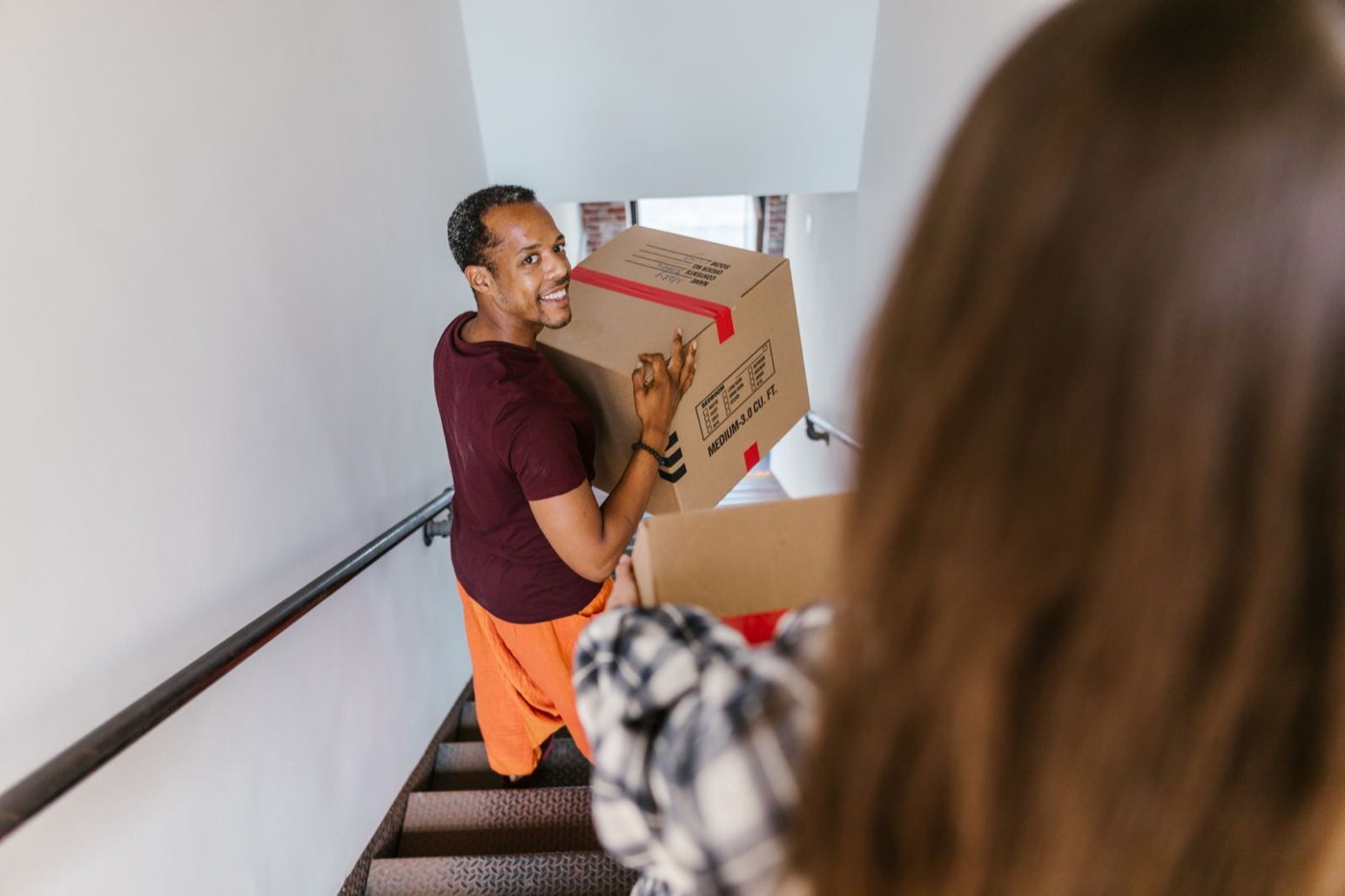 A man carrying a moving box down a flight of stairs