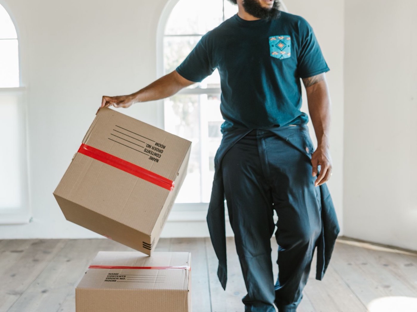 A mover with cardboard boxes in an empty room