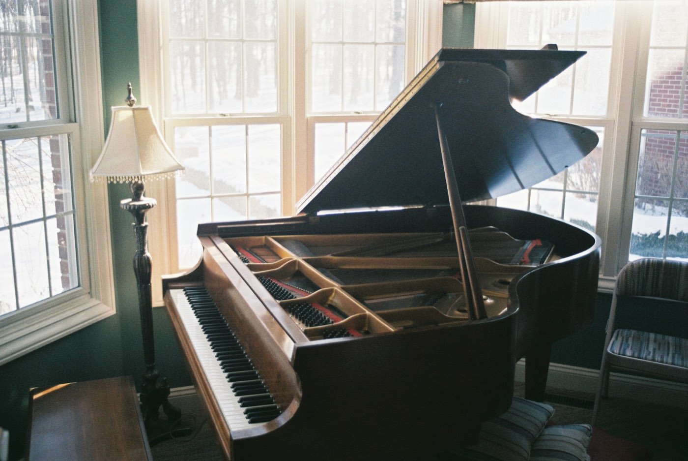 A grand piano in a living room beside a window