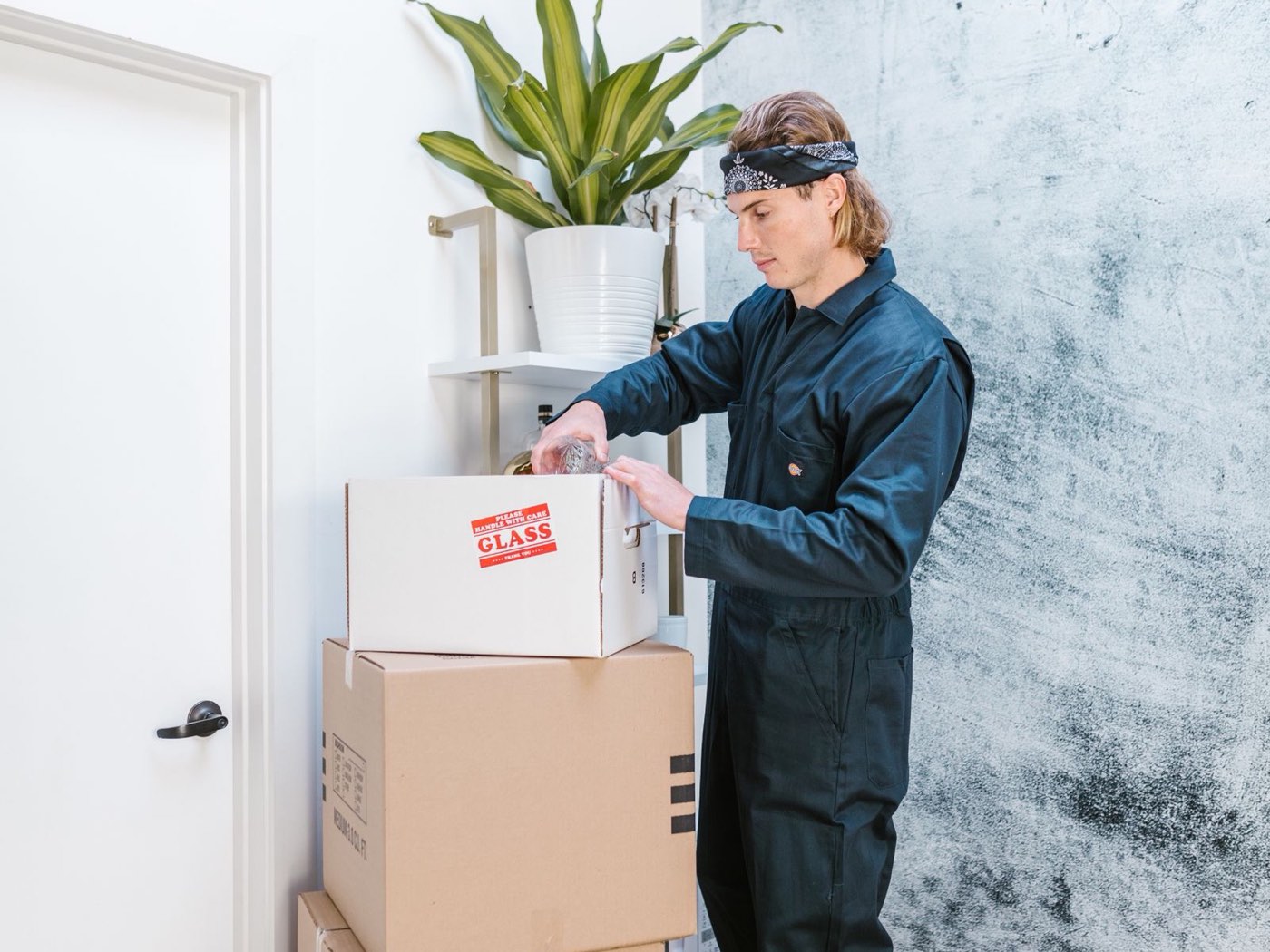A mover in overalls packing and stacking boxes